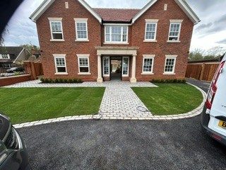 Large red-brick new-build house with a setts path, tarmac driveway and fresh lawns