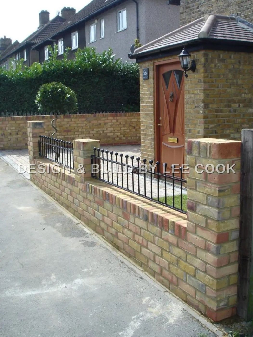 Yellow brick front wall with piers and black railings